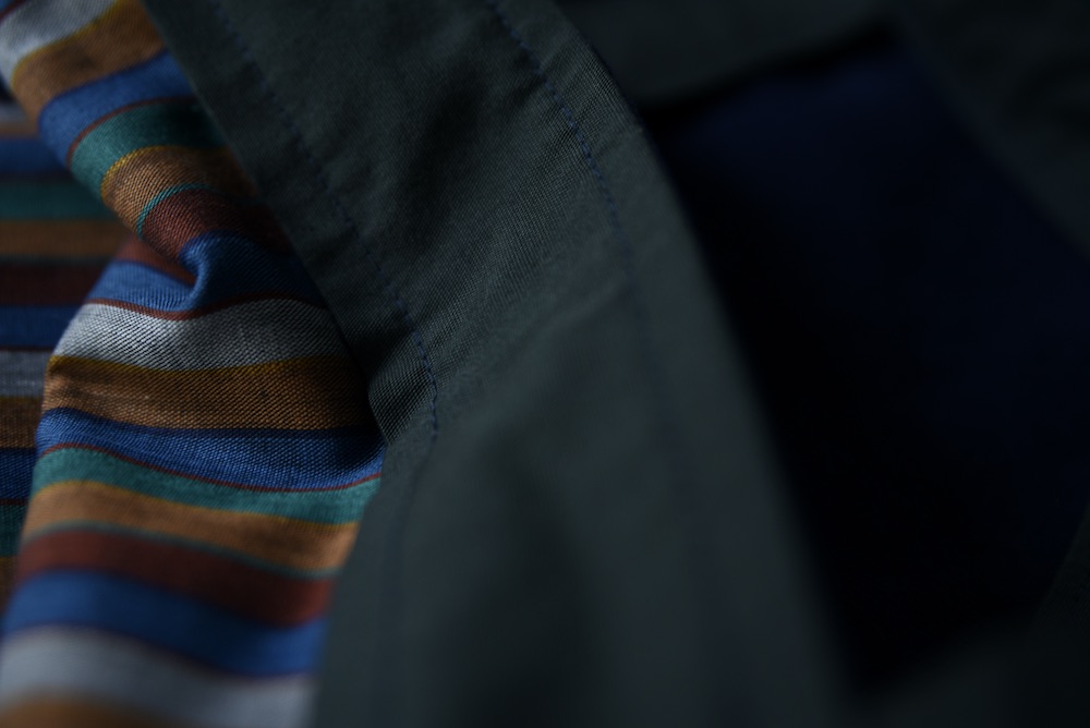 Dark green fabric in centre. Jewel coloured fabric running perpendicular on the left. Dark shadows on left.